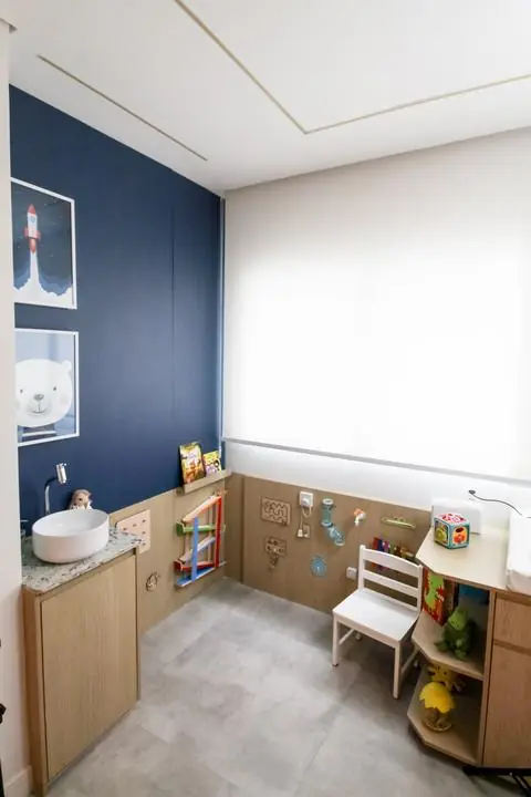 Espaço infantil com brinquedos de parede, livros e cadeirinha